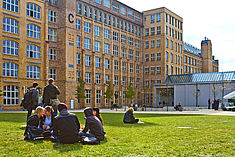 Studierende sitzen auf der Wiese im Innenhof vor Gebäude C am Erstsemestertag 