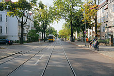 Eine Straße mit Straßenbahn und Wohnhäusern in Karlshorst